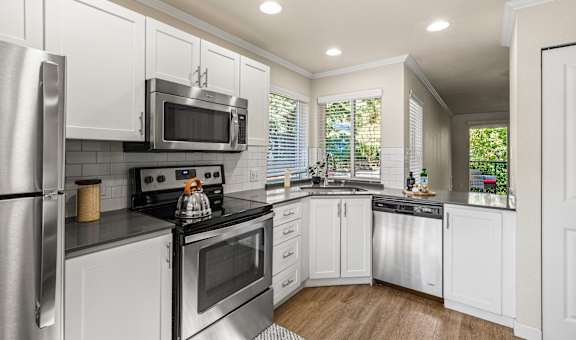 A modern kitchen with white cabinets and stainless steel appliances.