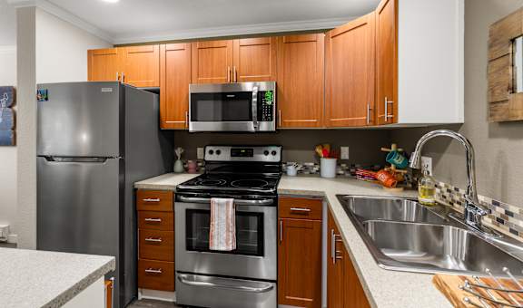 A kitchen with a stove, oven, refrigerator, microwave, and sink.