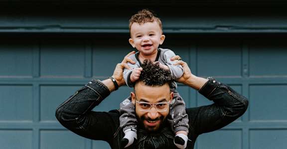 a man holding a child on his shoulders