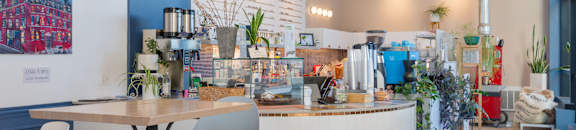 a cafe with a round table and chairs in front of a counter with coffee machines