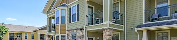 A sunny day at a residential complex with apartment buildings and green lawns at Wellington Grande Apartment Homes, Longview, Texas