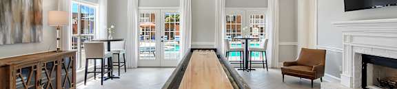 a long shuffleboard table in the middle of a living room with a fireplace at Bridgewater Apartment Homes, Mississippi 39047