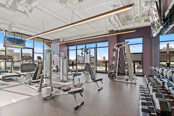 A gym with a variety of equipment including treadmills, weights, and exercise machines.