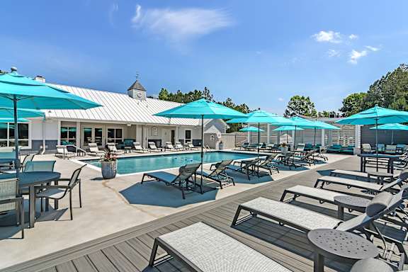 a swimming pool with chaise lounge chairs and a pool house in the background  at The Woodlands Apartment Homes, Meridian, Mississippi, 39301