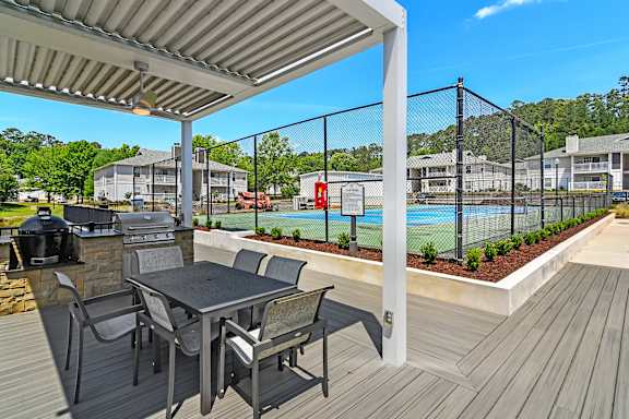 a covered deck with chairs and a bar and a fountain  at The Woodlands Apartment Homes, Meridian, Mississippi