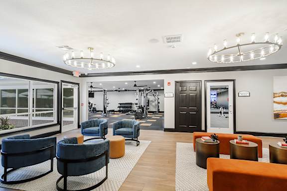 A spacious waiting area with blue and orange chairs and a large mirror on the wall. at The Woodlands Apartment Homes, Meridian, MS, 39301