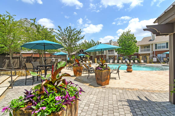 a swimming pool with chaise lounge chairs and a pool house in the background at Legacy Apartment Homes, MS, 39157