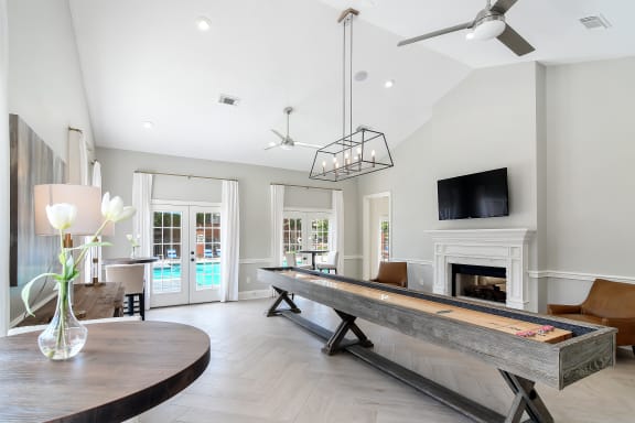 a long shuffleboard table in the middle of a living room with a fireplace at Bridgewater Apartment Homes, Brandon, MS 39047