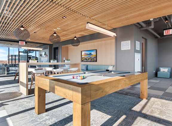 A pool table is in the middle of a room with a wooden ceiling.