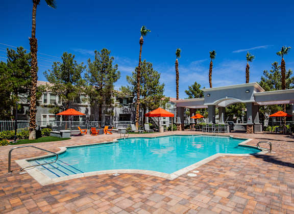A pool surrounded by palm trees and umbrellas.