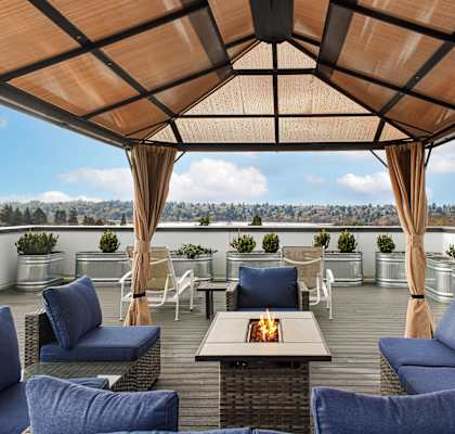 A patio with blue cushioned chairs and a table with a lit candle on it.