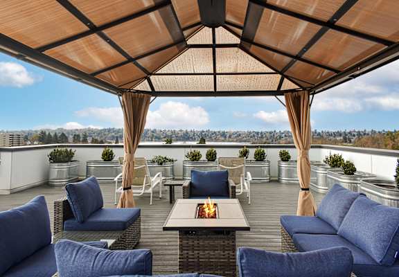 A patio with blue cushioned chairs and a table with a lit candle on it.