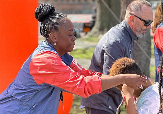 A woman in a blue and red jacket is holding a child.