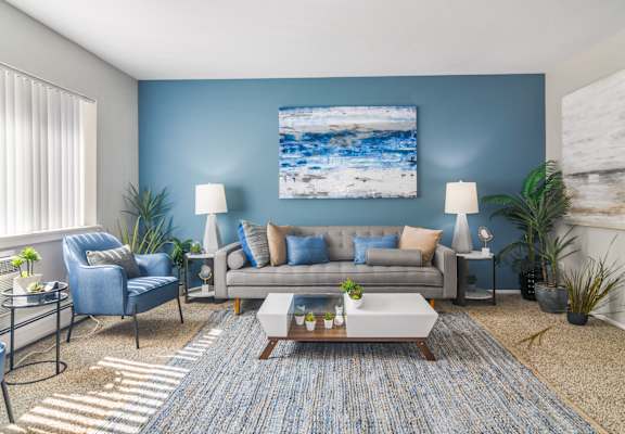 a living room with a blue accent wall and a gray couch  at ReNew Aurora, Aurora