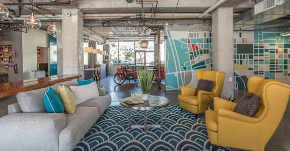 A modern living room with a grey couch, yellow chairs, and a patterned carpet at Herbert Residential, Tucson