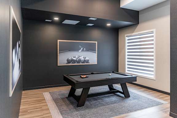 A pool table in a room with a picture on the wall.