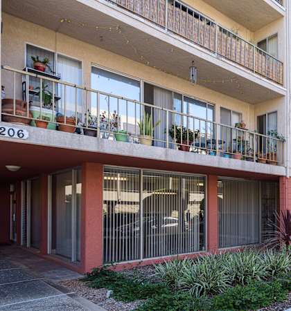 an apartment building with balconies and a sidewalk in front of it