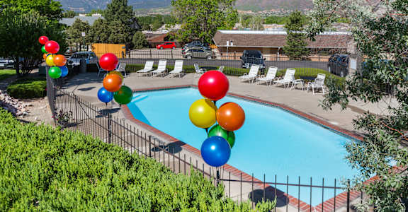 A pool surrounded by trees and balloons.