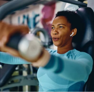 A woman in a blue top is working out on a machine in a gym. at Adelphi Quarter, Columbus, 43203