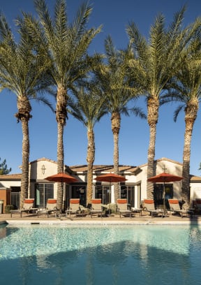 a swimming pool with chaise lounge chairs and umbrellas in front of a hotel