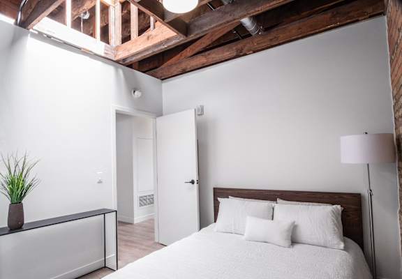 A bedroom with a bed and a ceiling with exposed beams  at Bostad Apartments, Fargo, North Dakota, 58102