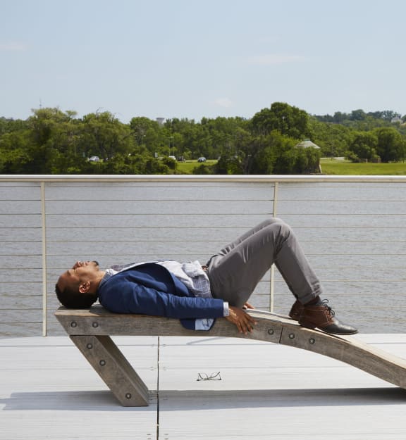 a man sleeping on a bench near a body of water