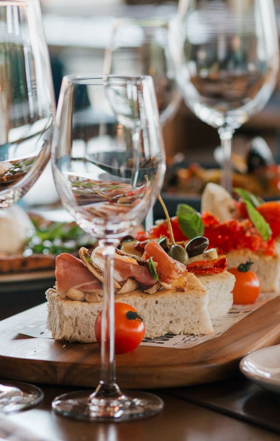a wooden table topped with plates of sandwiches and wine glasses