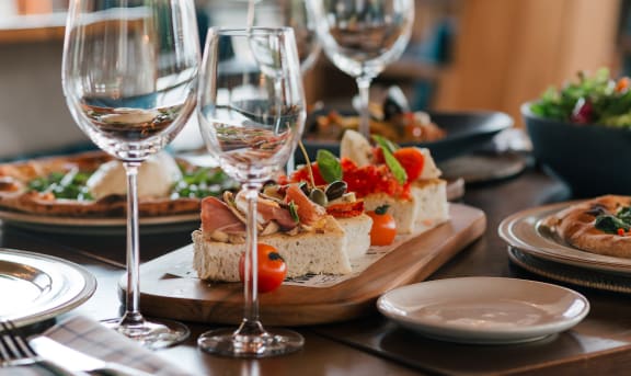 a wooden table topped with plates of food and glasses of wine