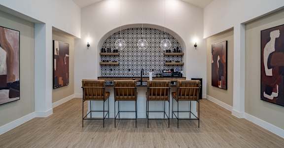 A modern kitchen with a bar area and chairs.