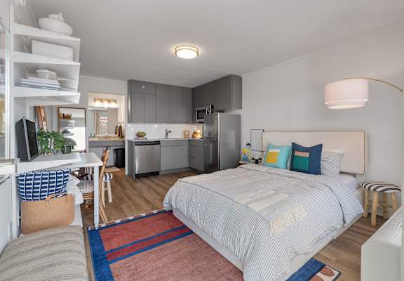 A bedroom with a bed, a desk, and a kitchen area. at The Teale Navy Yard, North Charleston, South Carolina