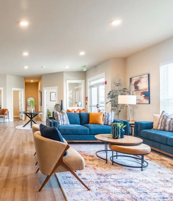 A living room with a blue couch and a wooden chair.