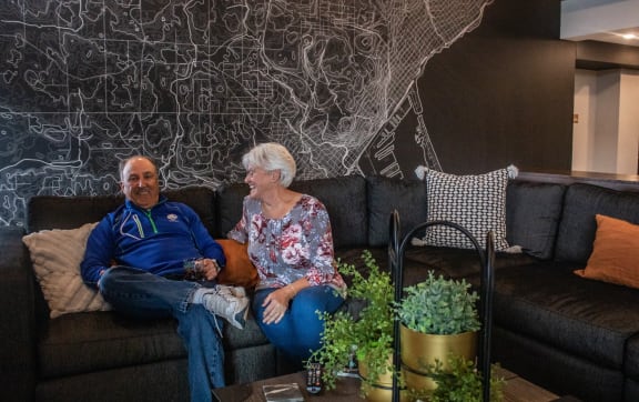 a man and woman sitting on a couch in front of a wall with a drawing at Vue at Bluestone, Duluth, Minnesota