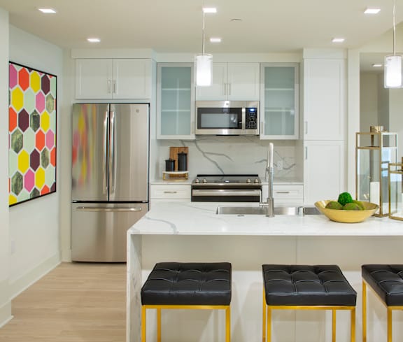 A kitchen with a white counter top and a fridge.