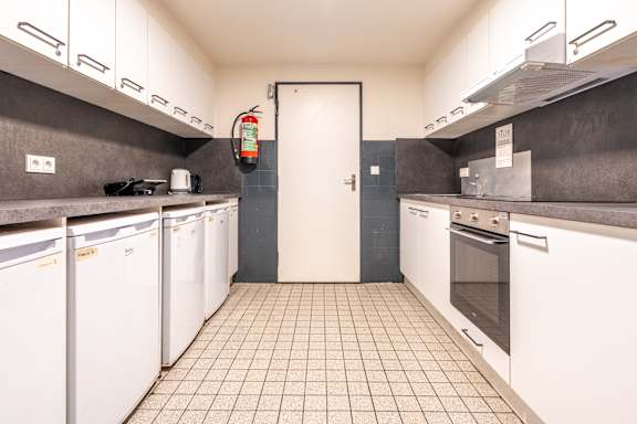 A kitchen with white appliances and a tiled floor.