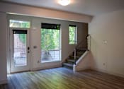 Thumbnail 3 of 5 - A room with a staircase and a door leading outside.