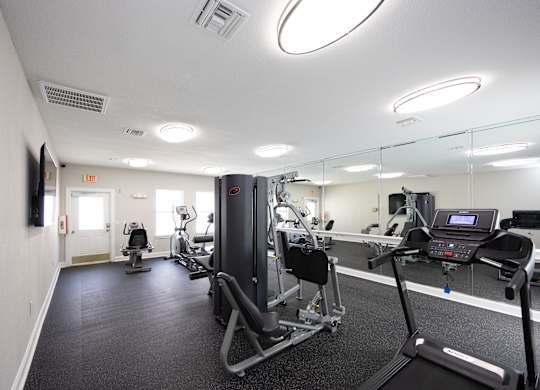 a gym with exercise equipment and mirrors in a building at Magnolia Pointe Apartments in Duluth, GA