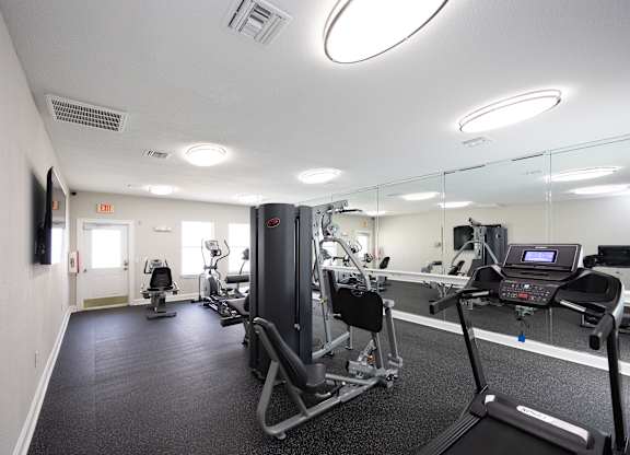 a gym with exercise equipment and mirrors in a building at Magnolia Pointe Apartments in Duluth, GA