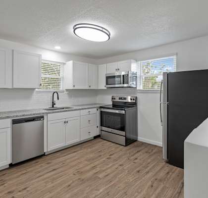 an empty kitchen with white cabinets and stainless steel appliances