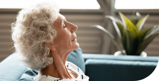 an older woman sitting on a couch with her eyes closed