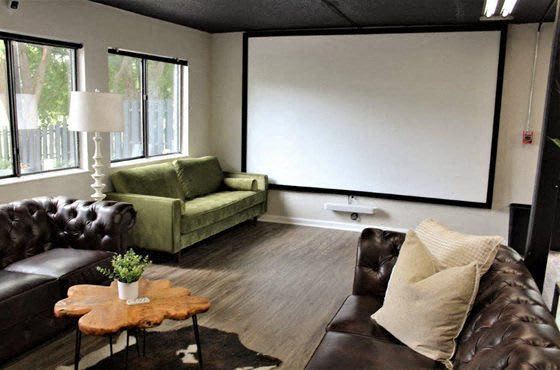a living room with leather furniture and a projector screen at Capital Flats & Magnolia Square Apartments, Raleigh, NC, 27601