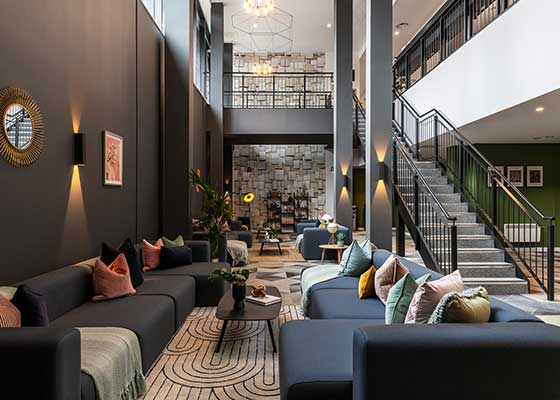 a lobby with couches tables and chairs and a staircase