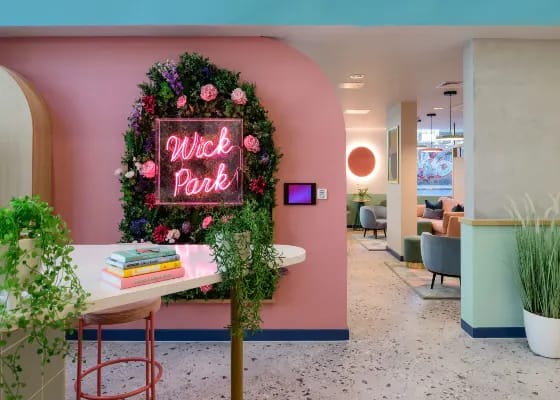 a pink wall with a pink sign on it and a pink table with some plants