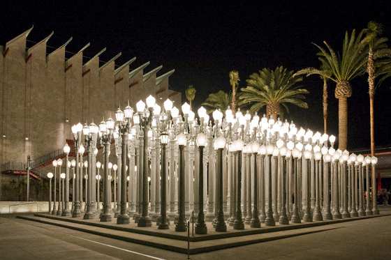 A long row of lighted street lamps are lined up on a sidewalk at The Urbanpolitan, Los Angeles, CA