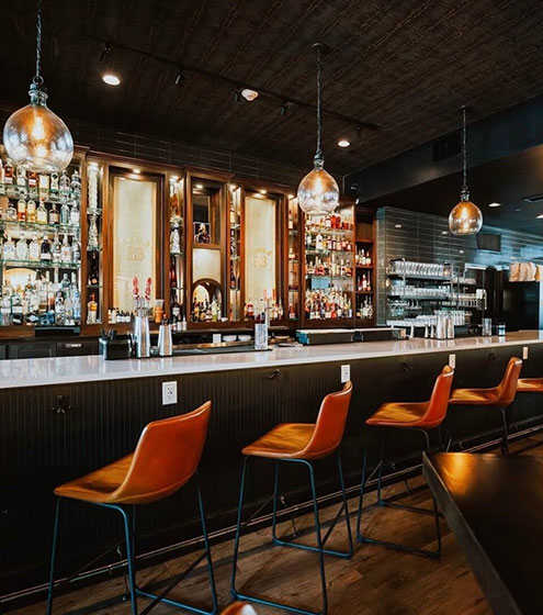A bar with orange chairs and a wooden counter.