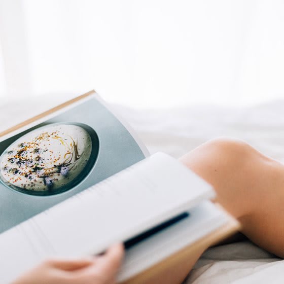 A person is reading a book with a dessert on the page.