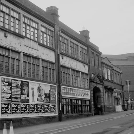 a black and white photo of a building with cars parked in front of it
