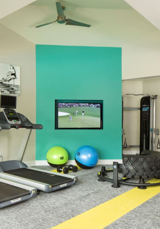 a home gym with a turquoise accent wall and a flat screen tv