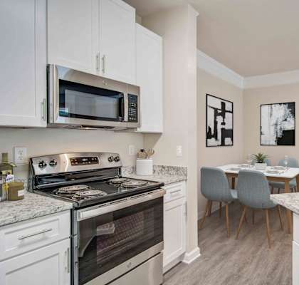 A kitchen with a stove, microwave, and a dining table with chairs.