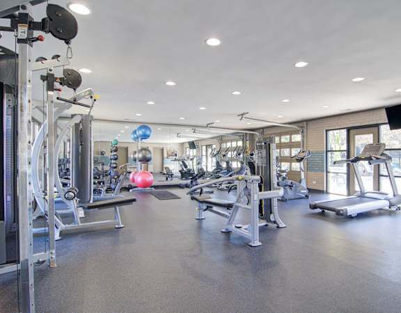 a spacious fitness center with cardio equipment and a pink exercise ball