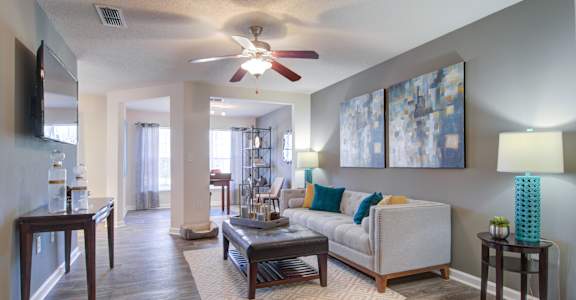 A living room with a white couch, a coffee table, and a ceiling fan.